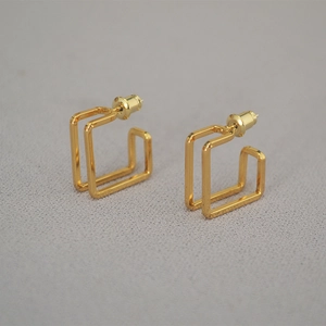 Macro shot of geometric double-frame gold stud earrings with polished finish