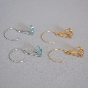 Detail of cage pyramid earrings with cubic zirconia inlay in gold and silver plating