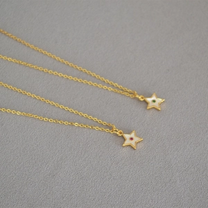 Detail of star-shaped pendants with shell inlay and colorful zircon on golden chains