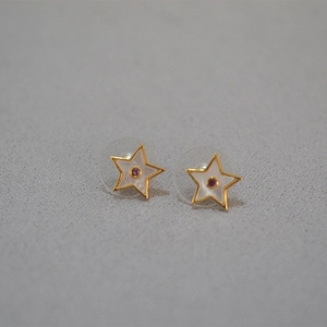 Vue macro de la boucle d'oreille étoile avec nacre et petite pierre précieuse rouge