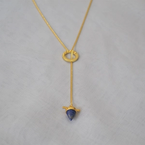 Detail of a vintage brass Y-chain necklace featuring a blue lapis lazuli cone pendant