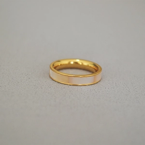 Détail d'une bague en laiton doré avec segments incrustés de nacre blanche