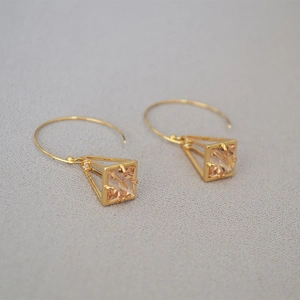 Detailed macro view of geometric birdcage earrings with inlaid champagne zircon stones
