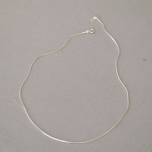 Dettaglio di una collana minimalista a catena a serpente d'argento con chiusura a molla