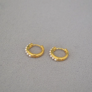 Detailed view of mini gold-plated hoop earrings featuring five small inlaid pearls