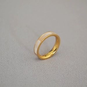 Vue macro d'une bague dorée avec incrustation de nacre blanche et finition lisse élégante