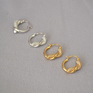Dettaglio di orecchini a nodo intrecciato in oro e argento con pavé di zirconi
