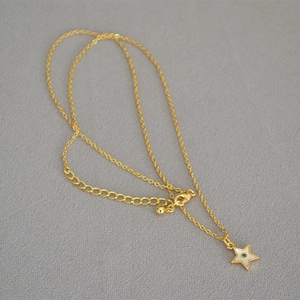 Detail of star pendant necklace with green zircon and mother of pearl on gold chain