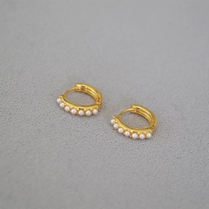 Close-up of minimalist gold-plated hoop earrings with six small white pearls in a neat row