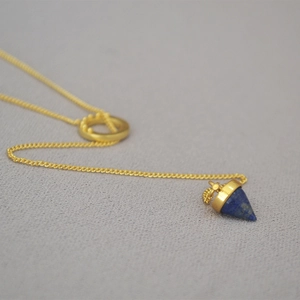 Vintage brass gold chain necklace with a lapis lazuli cone pendant on grey fabric