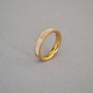 Vue détaillée d'une bague dorée polie avec une incrustation de nacre blanche irisée