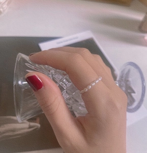 Close-up of elegant white freshwater pearl elastic ring worn by model on finger