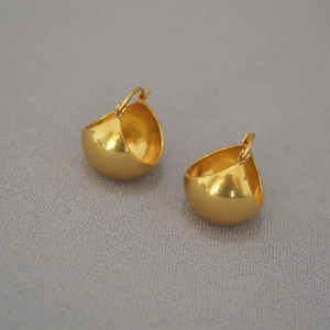 Macro shot of minimalist gold dome earrings with polished mirror finish and hook closure