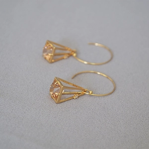 Macro view of gold-plated geometric cage earrings with champagne cubic zirconia stone