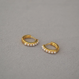 Detail of minimalist gold-plated hoop earrings with small pearls and clasp structure