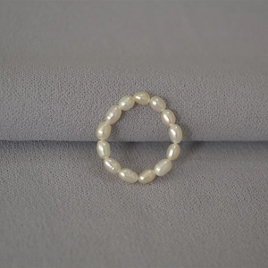 Elegant minimalist elastic freshwater rice pearl ring for women on grey fabric