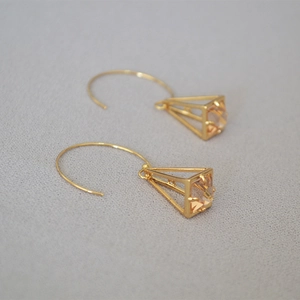 Detailed view of gold pyramid cage earrings featuring champagne faceted crystal inlays