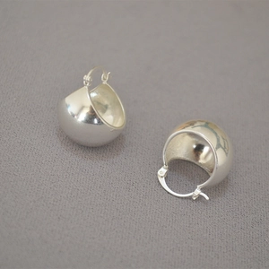 Macro detail of minimalist hollow spherical hoop earrings in high-polished finish