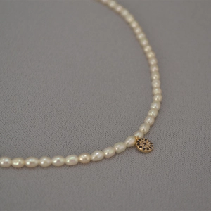 Macro shot of freshwater pearl necklace with evil eye pendant and crystal inlay