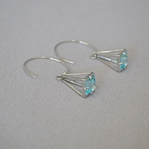 Detail of geometric silver wire pyramid earrings with light blue faceted crystal stone