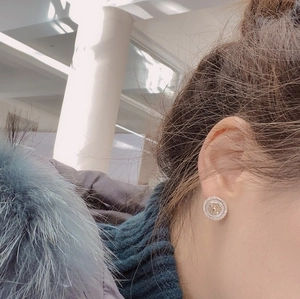 Détail de la boucle d'oreille camélia avec fleur dorée et bordure en zircone