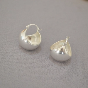 Macro shot of silver plated chunky hollow sphere earrings on textured grey fabric
