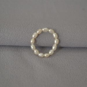 Detail shot of 13 natural white rice pearls strung on an elastic band for a minimalist ring