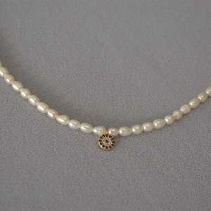 Freshwater pearl necklace featuring a vintage gold Evil Eye pendant with blue accents