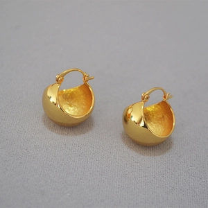 Detail of gold hollow dome earrings with polished exterior and matte textured interior