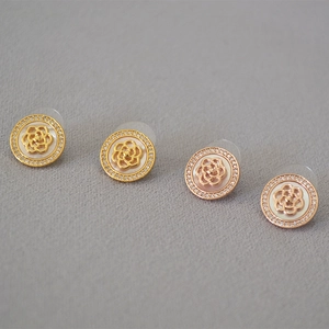 Détail macro de boucles d'oreilles camélia dorées et or rose serties de zircons fins