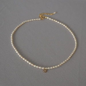 Detail of freshwater pearl necklace with a blue evil eye pendant and gold-plated clasp