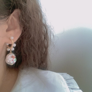 Detail of baroque pearl earrings with rose floral pattern and golden ring on model