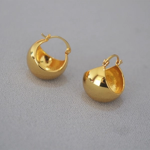 Macro detail of chunky gold hollow sphere hoop earrings with high polish brass finish