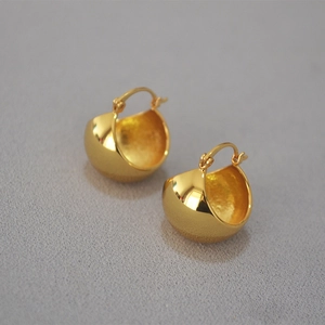 Macro shot of thick gold-plated dome hoop earrings with a polished metallic finish