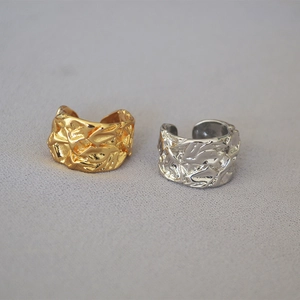 Close-up of hammered gold and silver wide band rings with irregular lava texture