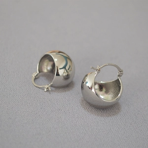 Macro shot of minimalist polished s925 silver hollow hemisphere earrings with secure clasp