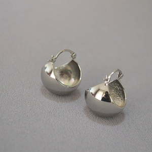 Macro shot of chunky silver hollow dome earrings with a high-polished metallic finish