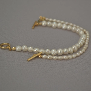Detail of elegant freshwater pearl bracelets featuring minimalist golden OT toggle clasps