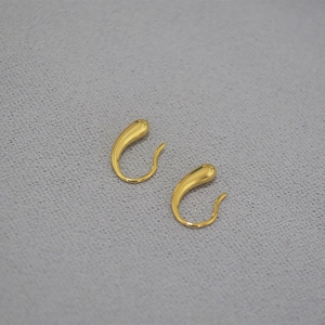 Detailansicht goldener Wassertropfen-Ohrringe mit poliertem Metall-Finish auf grauem Stoff