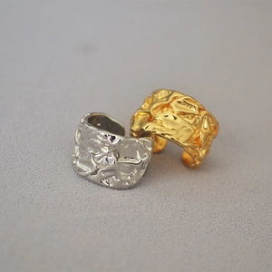 Detail of wide hammered gold and silver rings with irregular lava texture finish