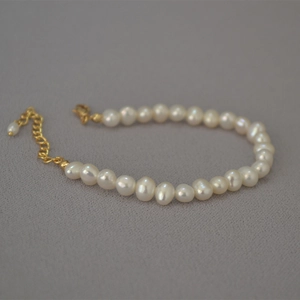Detailed macro view of white rice pearls with a golden lobster clasp and extension chain