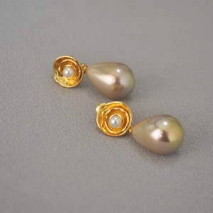 Detail of vintage gold flower stud earrings with large champagne water drop pearls
