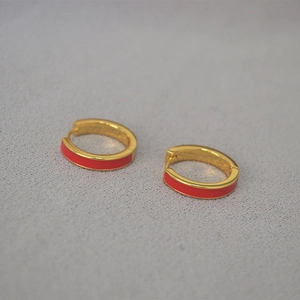 Détail macro de boucles d'oreilles en émail rouge avec bordure métallique dorée