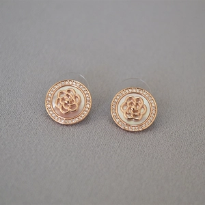 Détail de boucle d'oreille camélia en or rose avec nacre et pavage de zircons