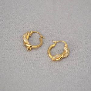Dettaglio di orecchini a nodo placcati in oro con zirconi micro-pavimentati