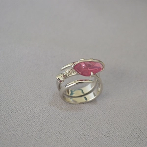 Dettaglio anello a spirale argento con pietra rosa e ciondolo a rosa
