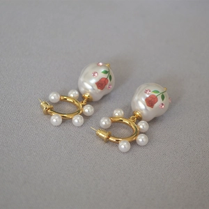Detail of baroque pearl earrings with red rose prints and pink crystal accents