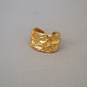 Macro view of wide gold-plated lava texture irregular hammered surface open ring