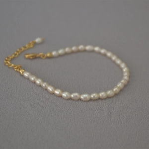 Detailed shot of irregular freshwater seed pearl bracelet with gold lobster clasp and chain