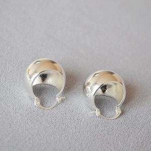 Detailed macro view of high-polished hollow ball hoop earrings in 18k gold plated brass